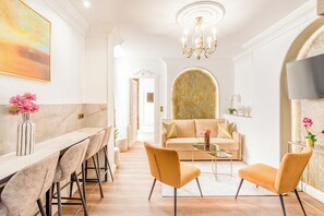 A modern living room with a sofa, two armchairs, a coffee table, and a chandelier. - Merveil - Luxury Suite - Louvre - Rousseau (Paris)