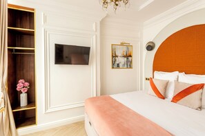 A bedroom with a bed, a television, a painting, and a wardrobe.
