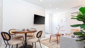 A modern living room with a sofa, a coffee table, and a dining area with a round table and chairs. - Genteel Home Constitución IV (Seville)