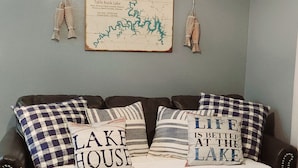 Een slaapkamer met een bed, twee kussens met tekst, een kaart aan de muur en twee macramé wanddecoraties.