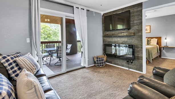 Een moderne woonkamer met een open haard, een bank en uitzicht op een terras.