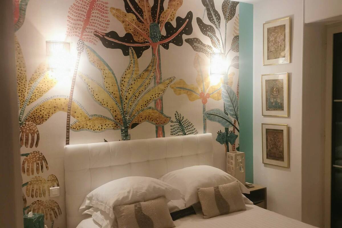 Ein Schlafzimmer mit einem großen Bett, zwei Nachttischen und einer Wandmalerei.