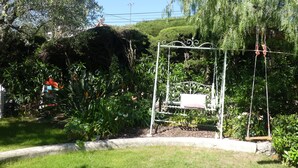 A garden with a swing set, surrounded by lush greenery and a variety of plants. - Blue Dream Cannes Guesthouse (Cannes)