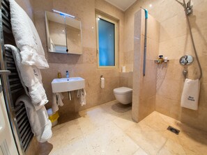 A modern bathroom with a white sink, a toilet, a shower with a glass door, and a towel rack with multiple towels. - Blue Dream Cannes Guesthouse (Cannes)