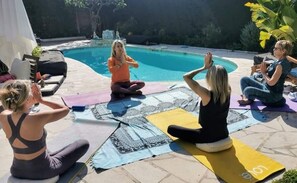 A group of people sitting on yoga mats in a backyard with a swimming pool. - Blue Dream Cannes Guesthouse (Cannes)