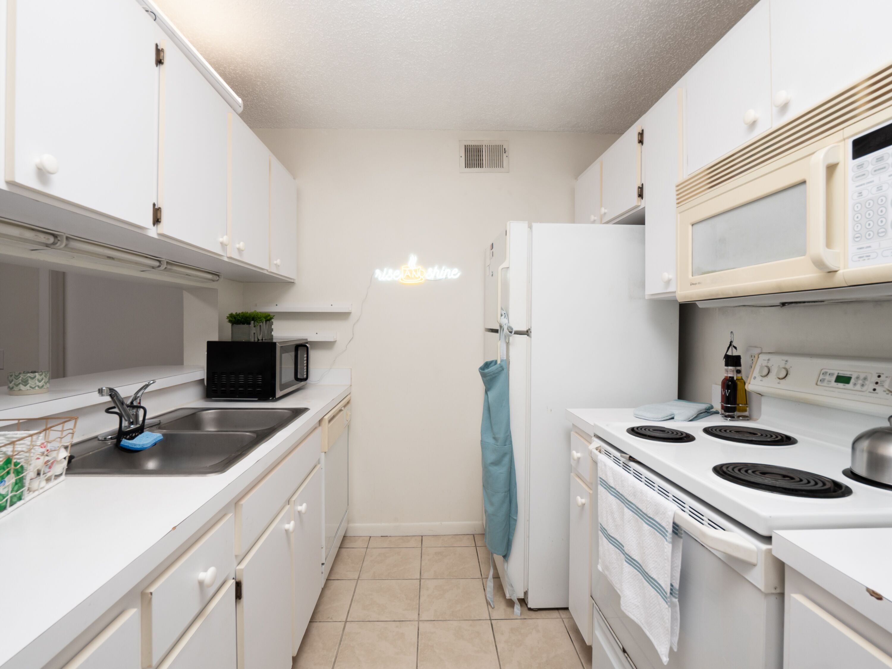 A compact kitchen with white cabinets, a black microwave, a white refrigerator, and a stove.