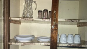 A kitchen shelf with stacked plates, a pitcher, and salt and pepper shakers. - Marthie Homeaway (Dodoma)