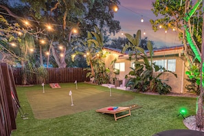 Un jardin avec un green d’entraînement, un support de départ en bois et une balle de golf.