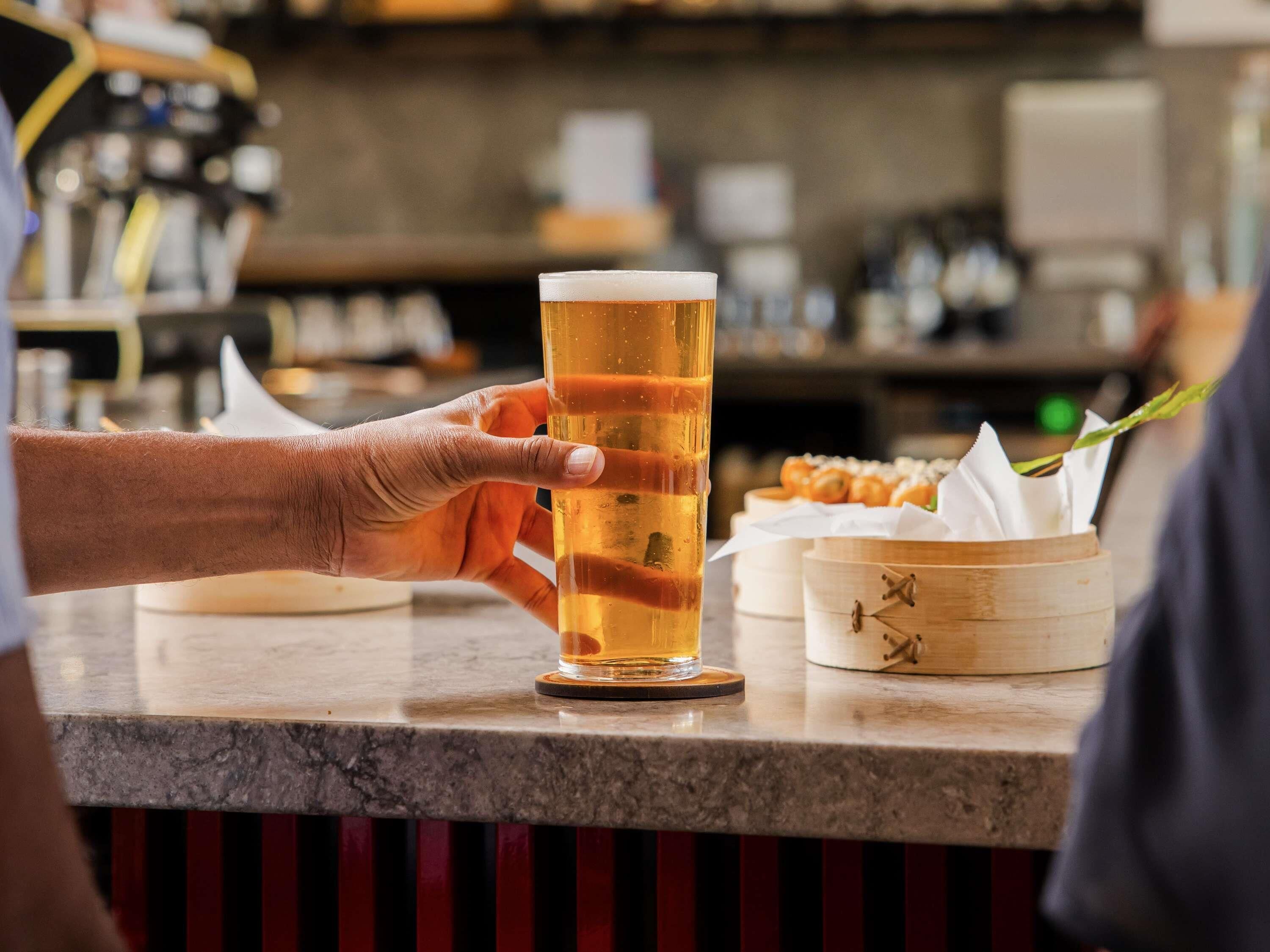 Un bar con una jarra de cerveza, un menú y un recipiente de madera con comida.