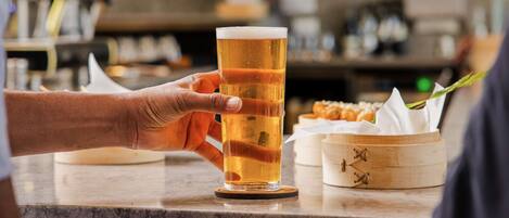 Une scène de bar avec un verre de bière, un menu et un récipient en bois contenant des aliments.