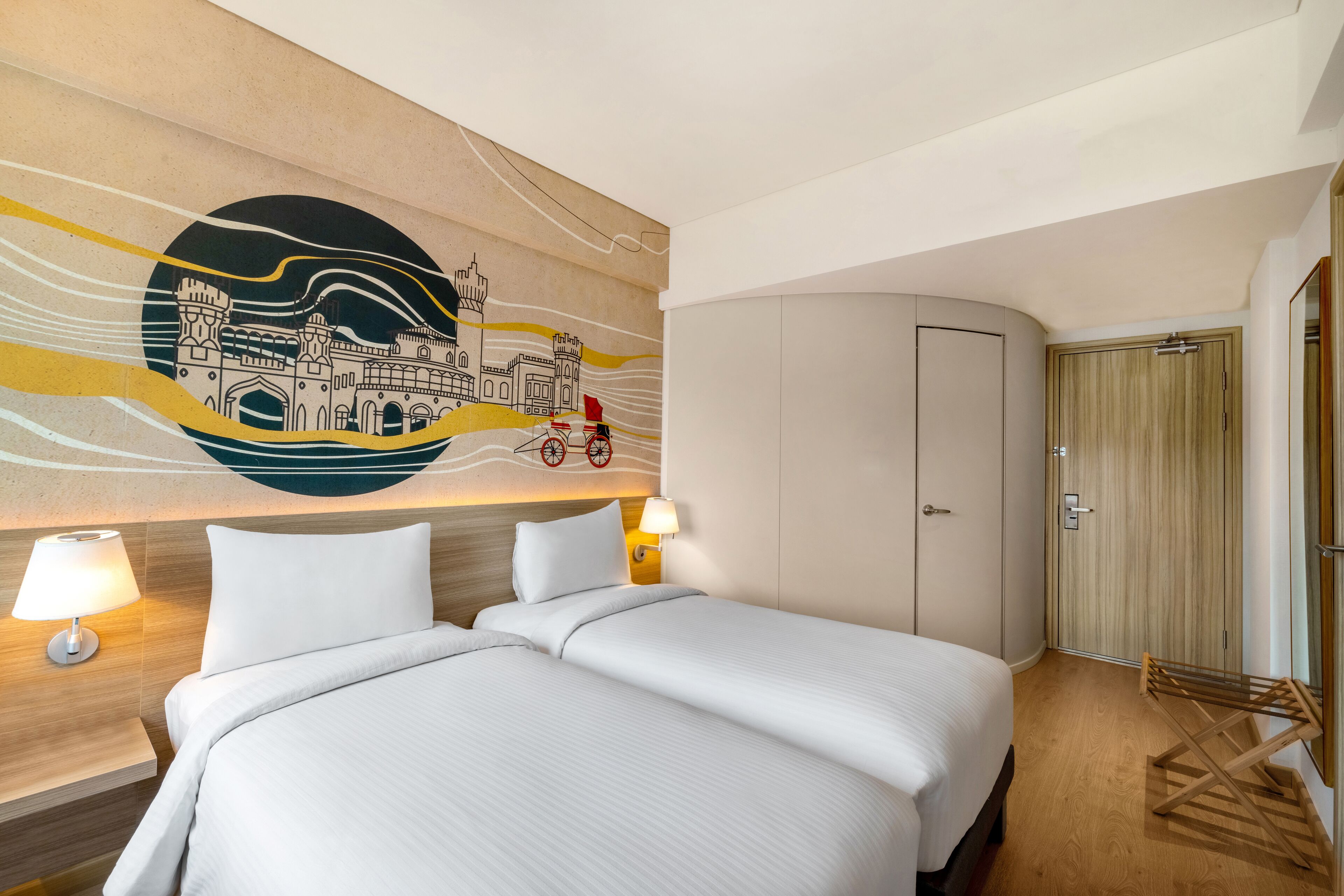 A hotel room with two beds, a wall mural, a wardrobe, and a wooden floor.