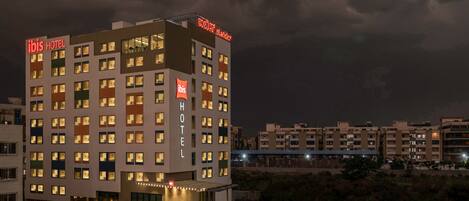 Un hotel de varios pisos con ventanas iluminadas y un llamativo letrero que dice