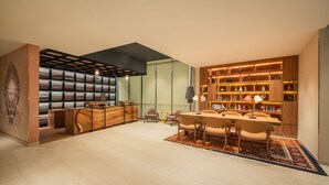 Una biblioteca moderna con un mostrador de recepción de madera, estanterías y un área de descanso con sillas y mesas.