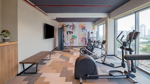 Un gimnasio moderno con equipo de ejercicio, una banca y un televisor en la pared.