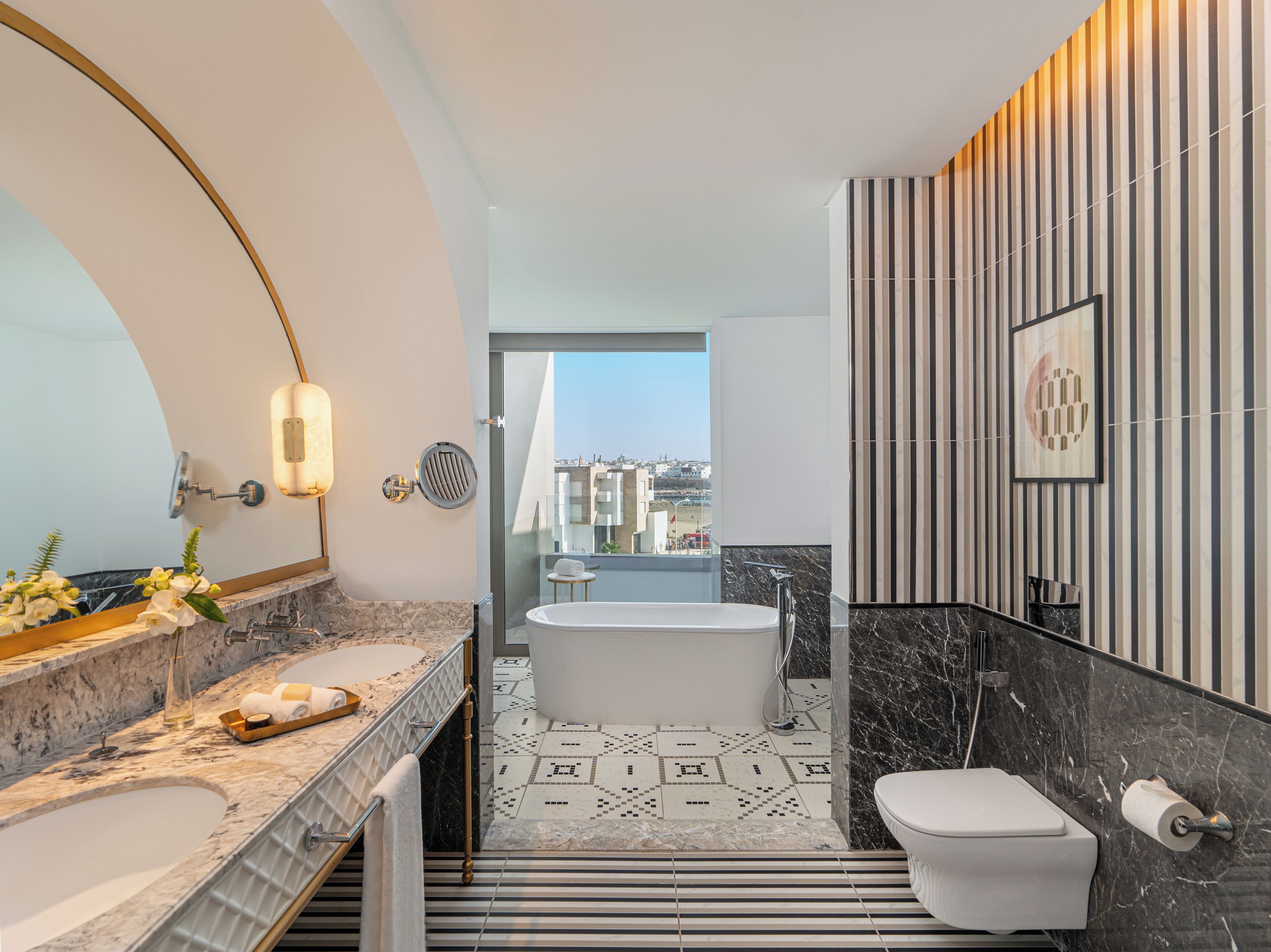 Een moderne badkamer met een ruime badkuip, een apart toilet en een wastafel met een marmeren aanrecht.