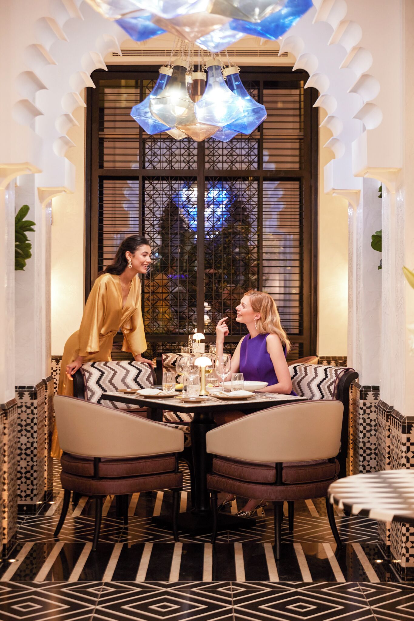 A dining area with a patterned floor, a table set with plates, glasses, and a decorative centerpiece.