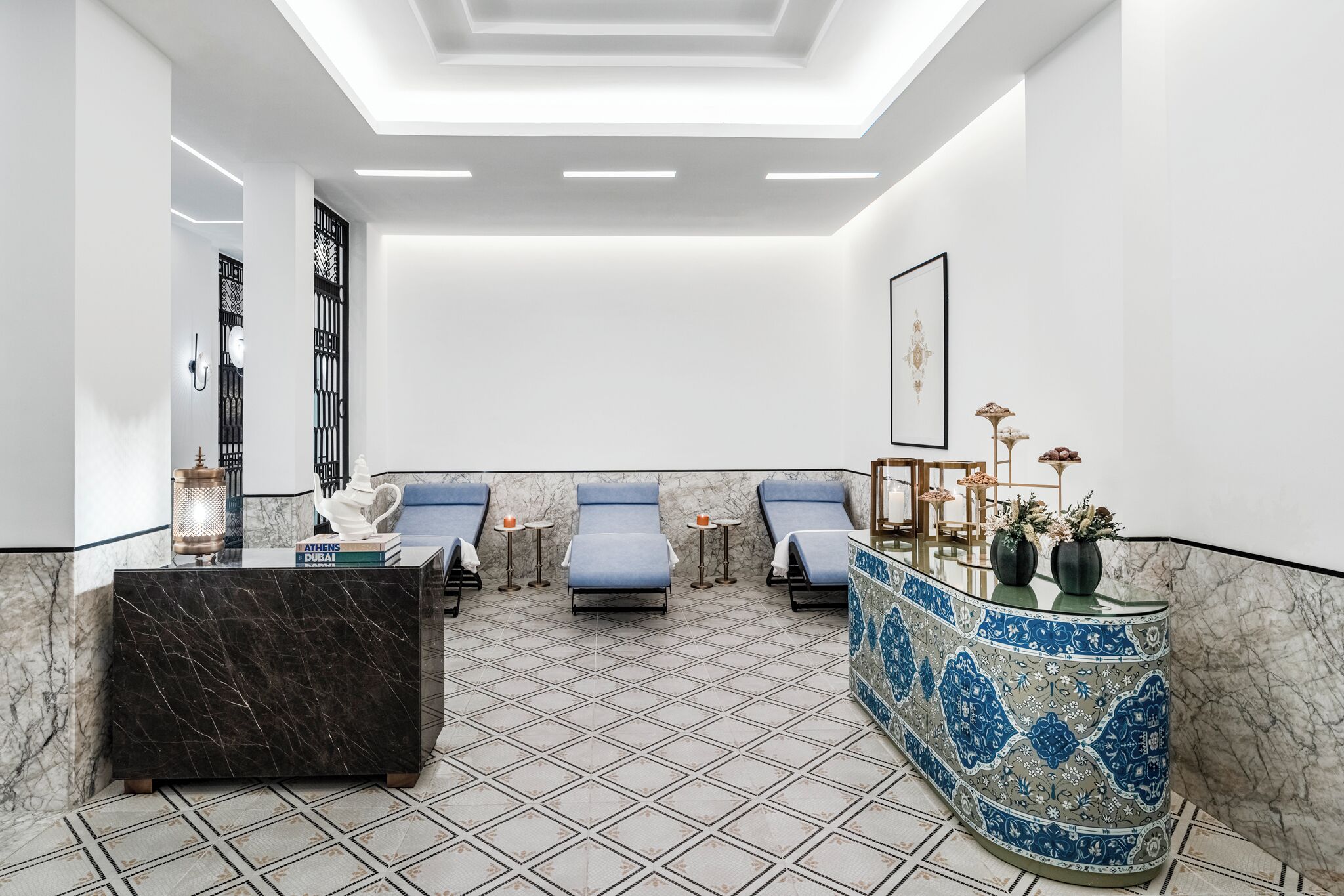 A modern spa area with a marble floor, a reception desk, and three lounge chairs.