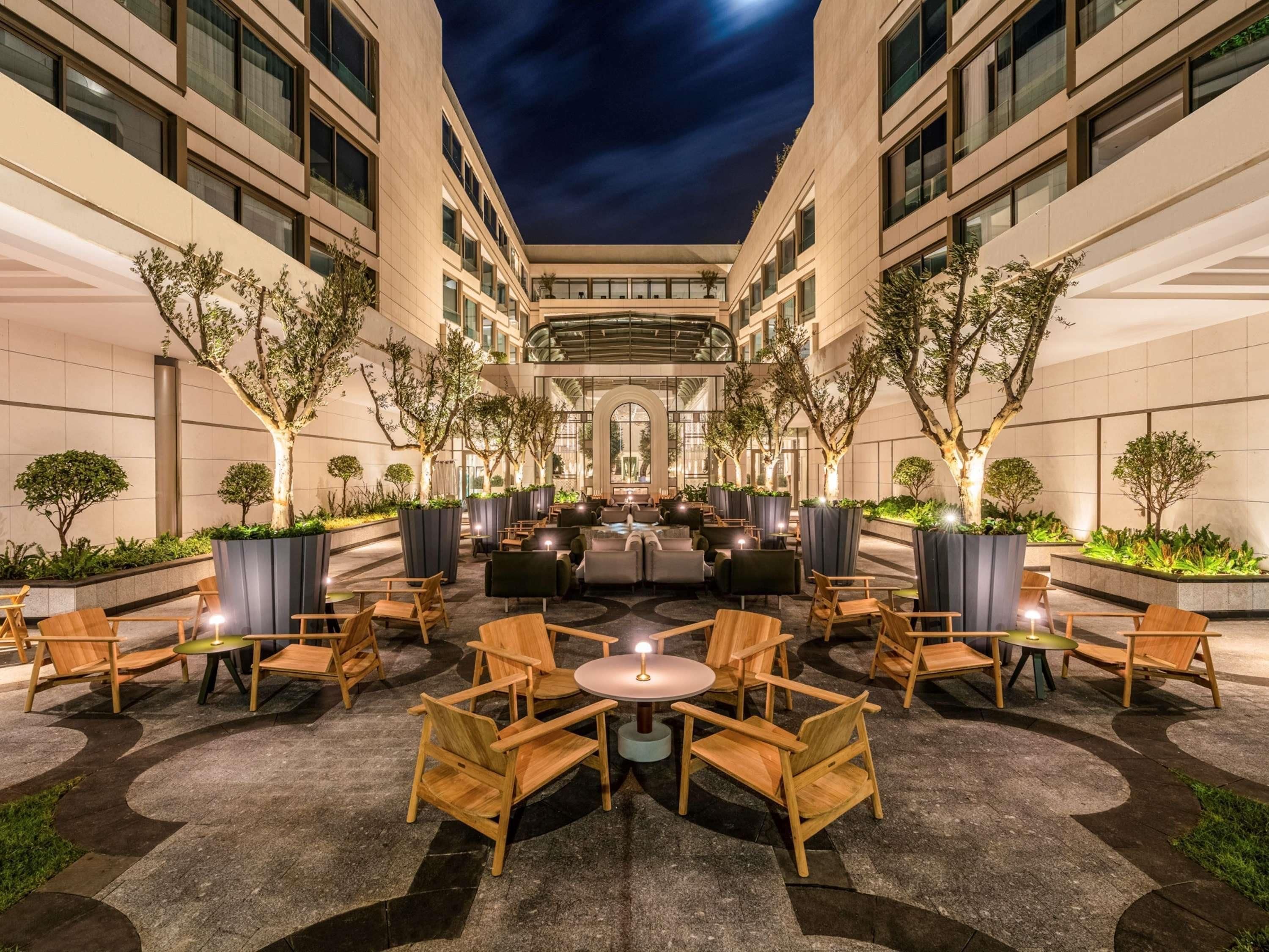 A courtyard with outdoor seating, potted plants, and a central lounge area.
