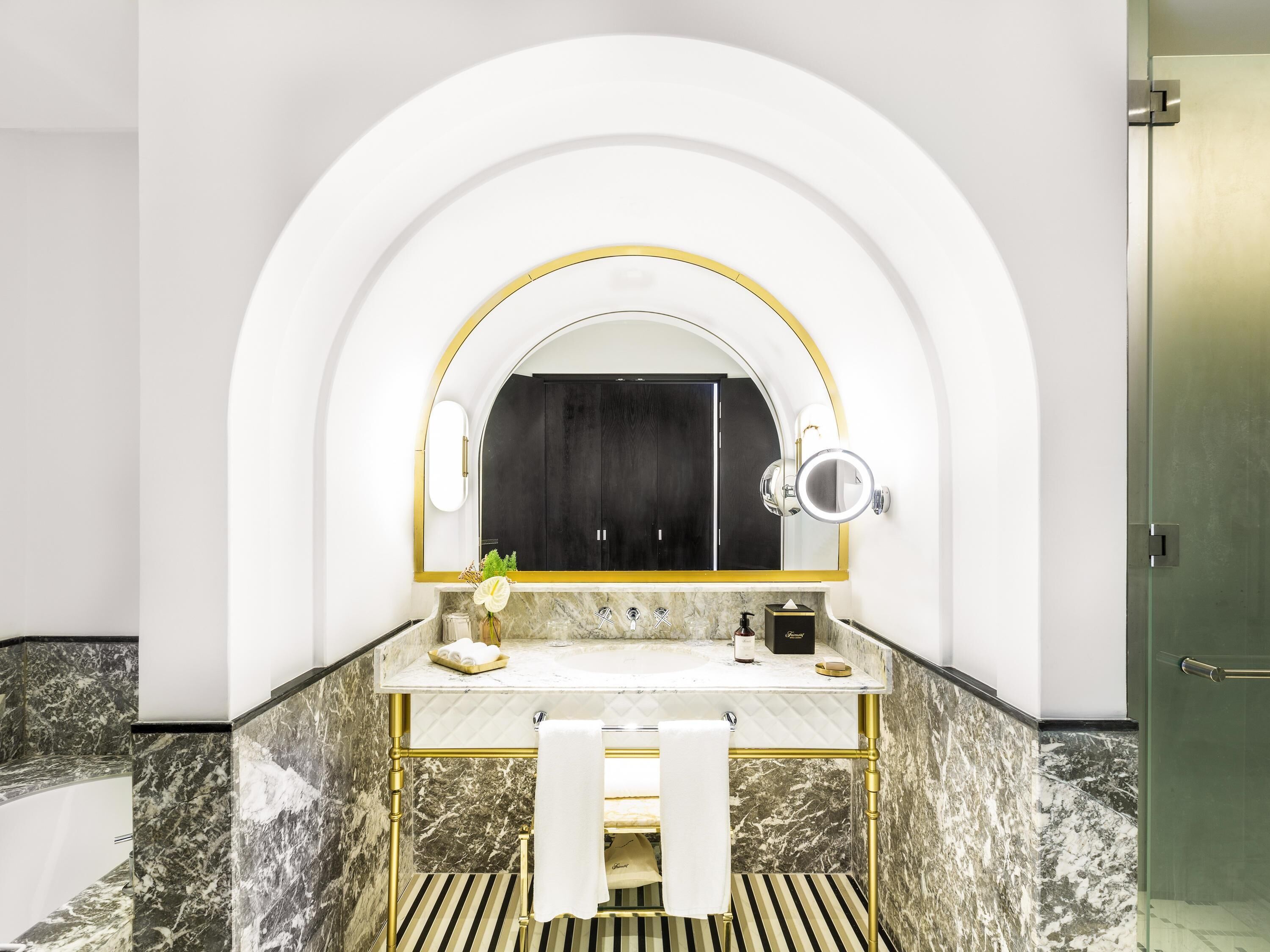 A modern bathroom with a marble vanity, a large mirror, and a towel rack.