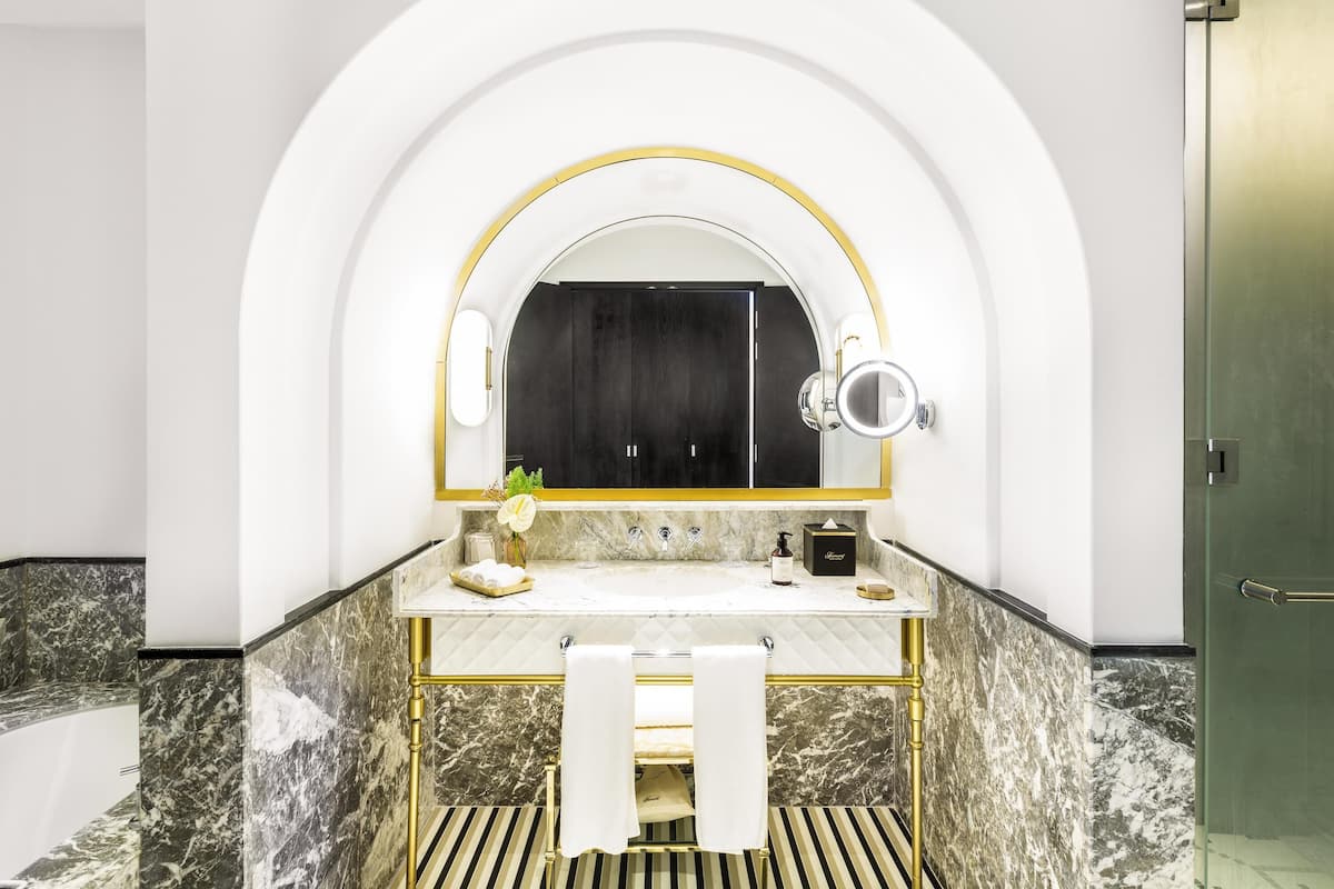 A modern bathroom with a marble vanity, a large mirror, and a towel rack.