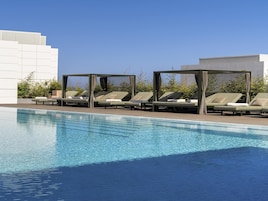 Una piscina al aire libre, sillones reclinables de piscina