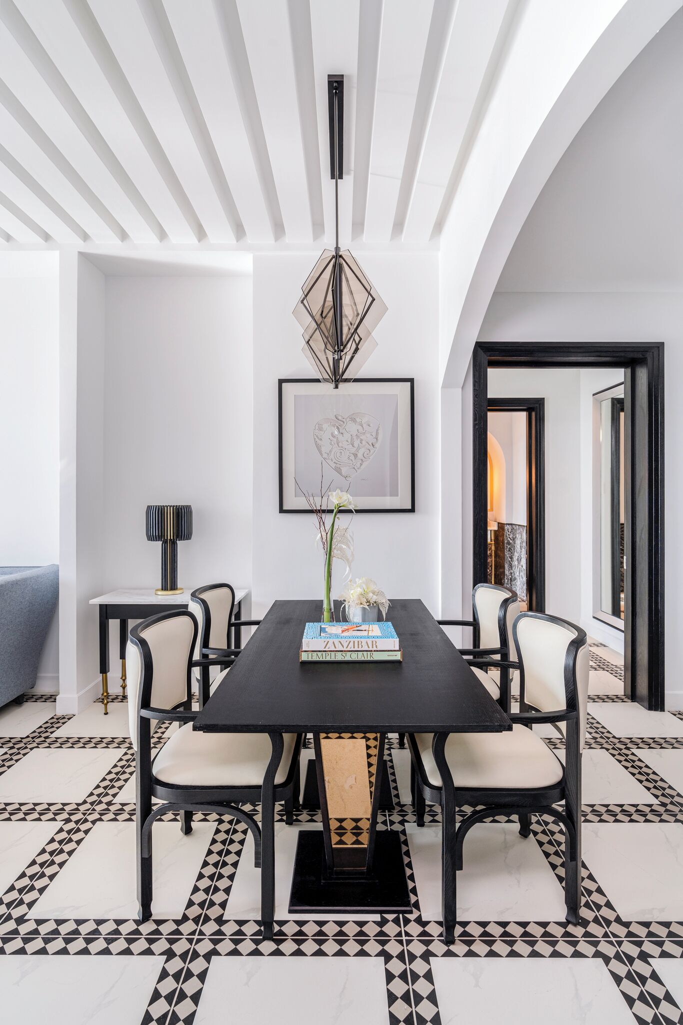 A dining area with a black table, white and black patterned floor, and modern chairs.