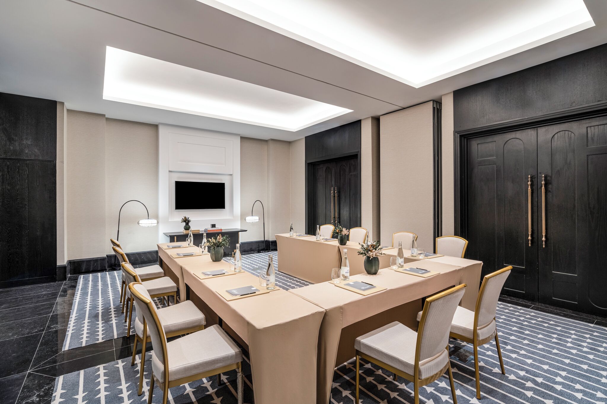 A conference room with a long table, chairs, a TV, and a large door.