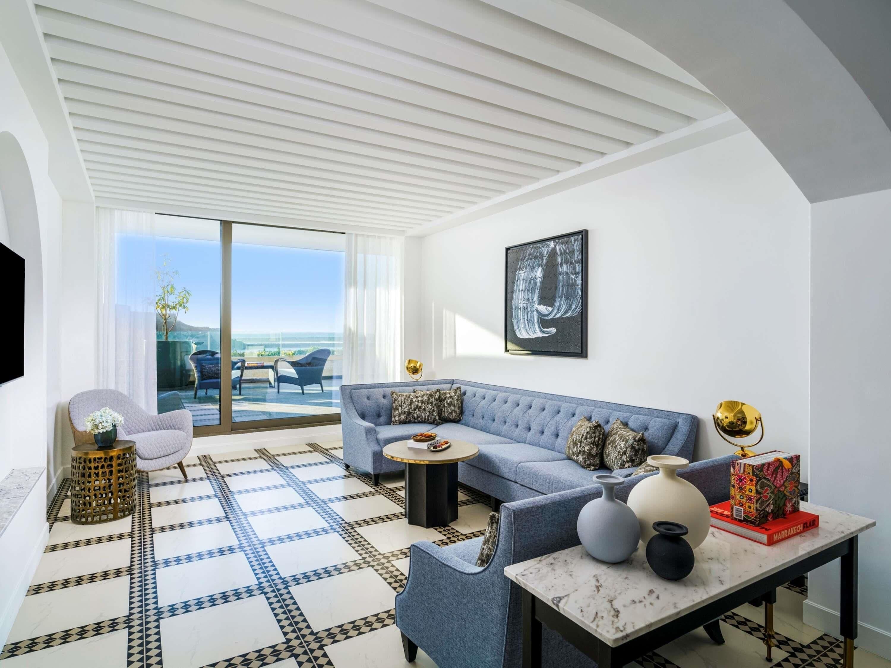 A modern living room with a sofa, armchairs, a coffee table, and a TV.