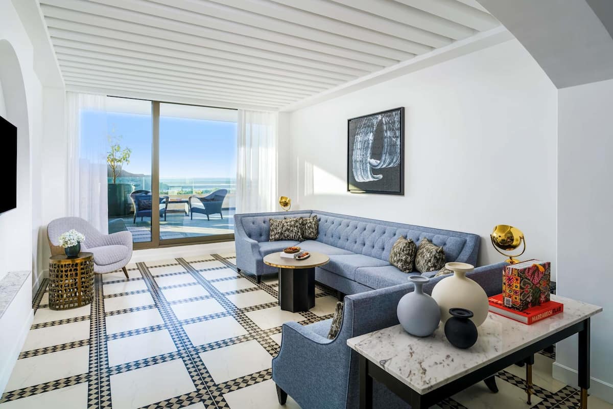 A modern living room with a sofa, armchairs, a coffee table, and a TV.