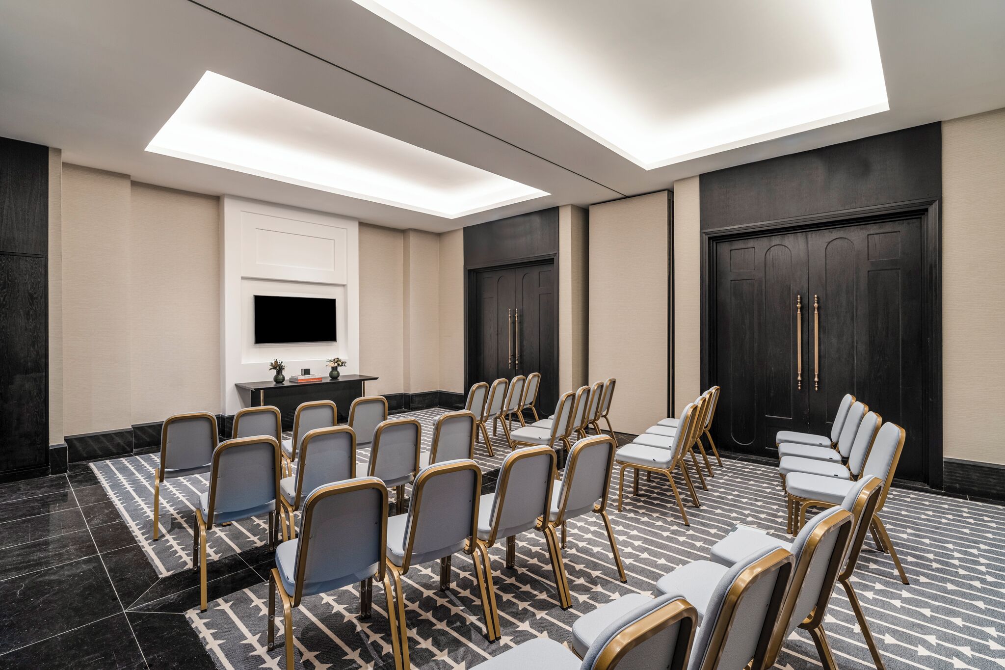 Une salle de conférence avec des rangées de chaises, un téléviseur et une porte noire.