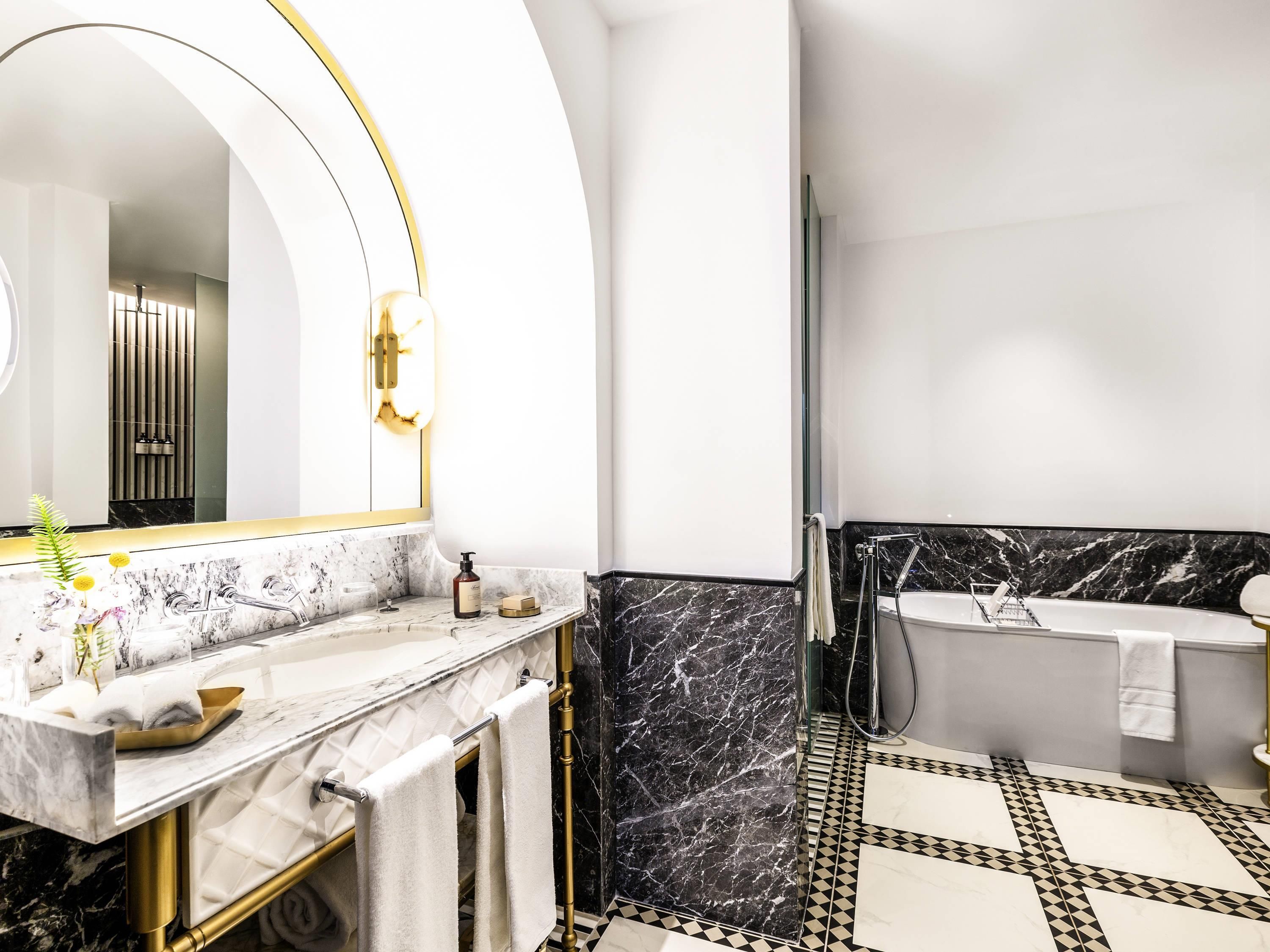 Une salle de bain moderne avec un meuble-lavabo en marbre, un grand miroir, une baignoire et un espace douche.