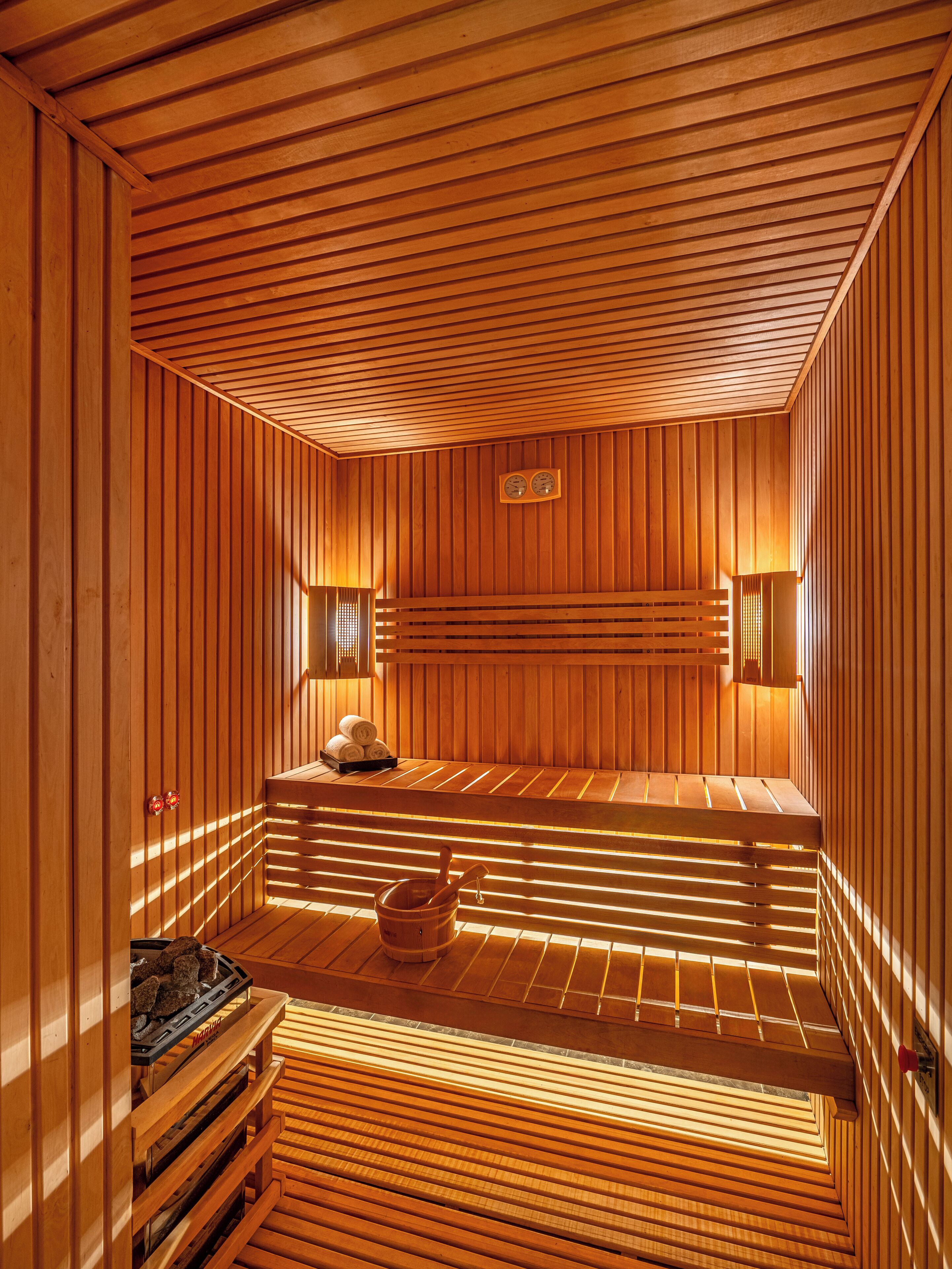 Una sauna con listones de madera, bancos y un cubo.