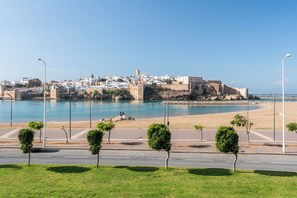 Un paysage urbain côtier avec un centre historique fortifié, une plage de sable et un ciel bleu dégagé.