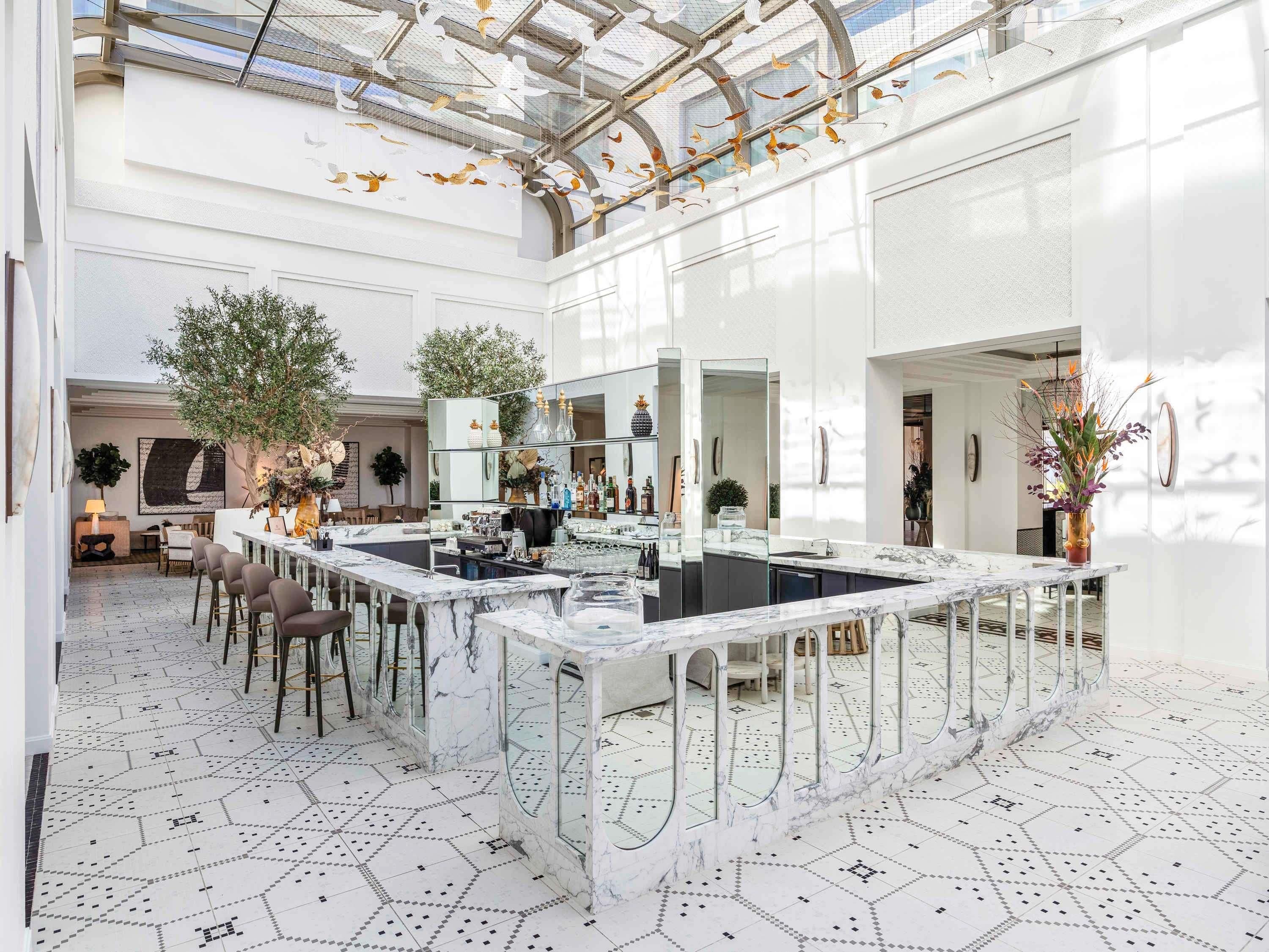 A spacious, modern kitchen with a marble island, large windows, and a high ceiling with a glass structure.