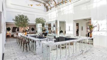 A spacious, modern kitchen with a marble island, large windows, and a high ceiling with a glass structure.