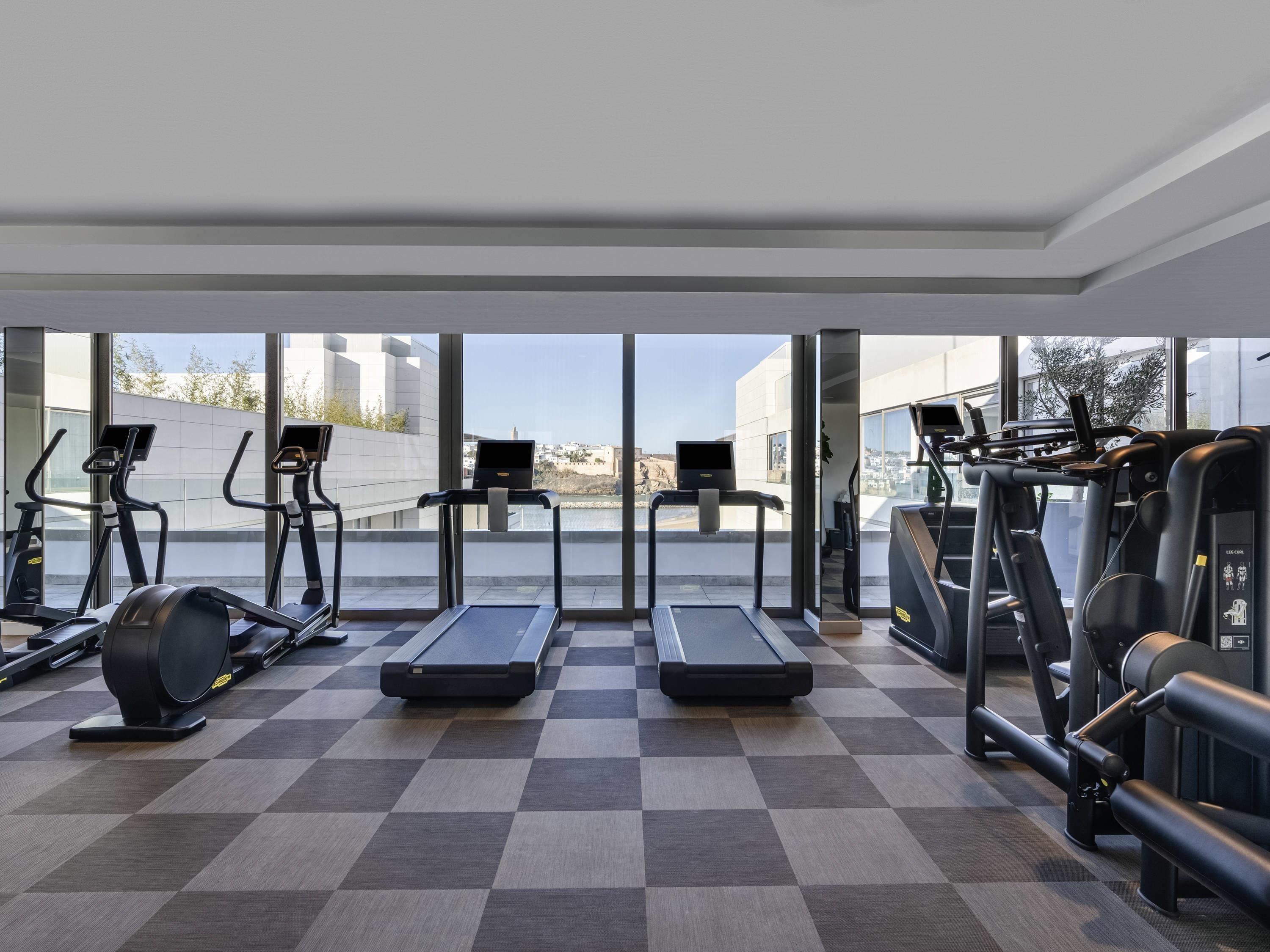 Uma academia com esteiras, elípticos e equipamentos de musculação.
