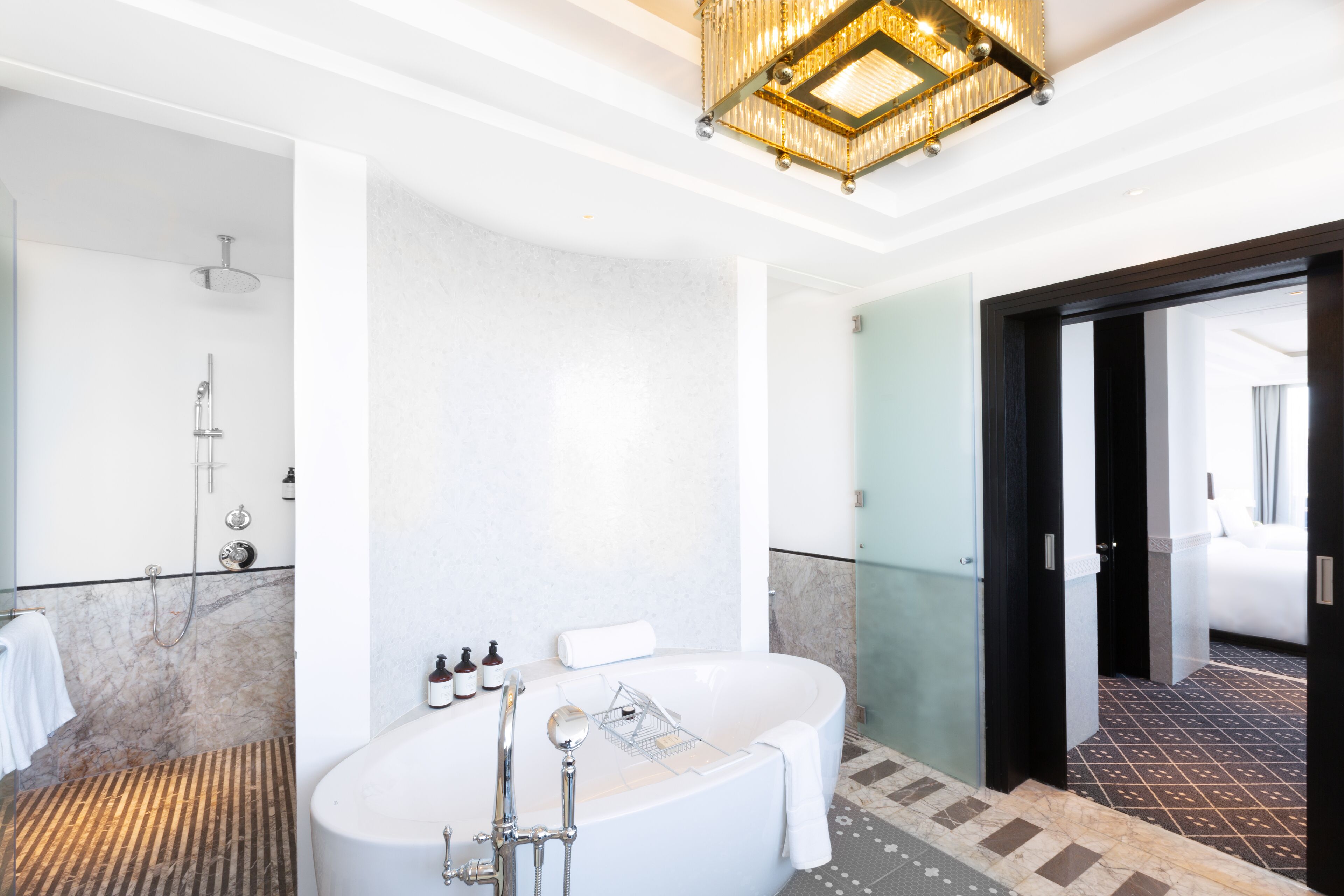 Une salle de bain moderne avec une baignoire sur pieds, une douche et une porte en verre donnant sur une chambre.