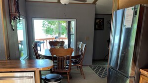 Une cuisine équipée d’une table à manger en bois, de chaises, d’un réfrigérateur, d’un lave-vaisselle et d’un ventilateur de plafond.