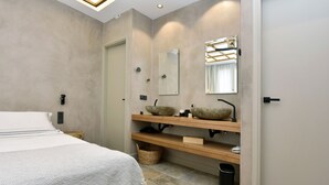 A modern bathroom with a large bed, two stone sinks, a mirror, and a wooden shelf. - Condo with private pool - 5 minutes from the beach (Pollonia)