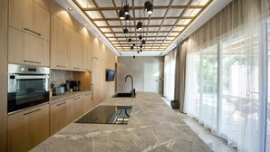 A modern kitchen with wooden cabinets, a built-in oven, and a large island with a glass top. - Condo with private pool - 5 minutes from the beach (Pollonia)