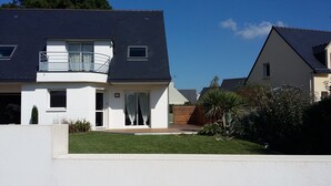 A modern two-story house with a balcony, a front door, and a small garden area. - Everything on foot and in the peace and quiet! (Pléneuf-Val-André)