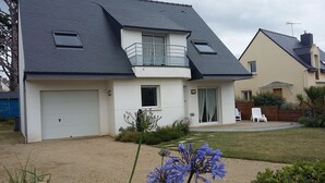 A two-story house with a dark roof, a white garage, and a small balcony. - Everything on foot and in the peace and quiet! (Pléneuf-Val-André)