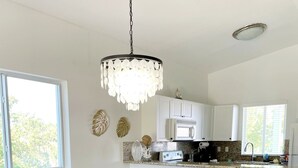 Ein Essbereich mit einem Holztisch und Stühlen, einer Chandelierleuchtre und einer Küche im Hintergrund.