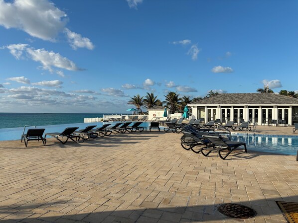 Un espace aménagé au bord de la piscine, avec des chaises longues et une vue sur l’océan.