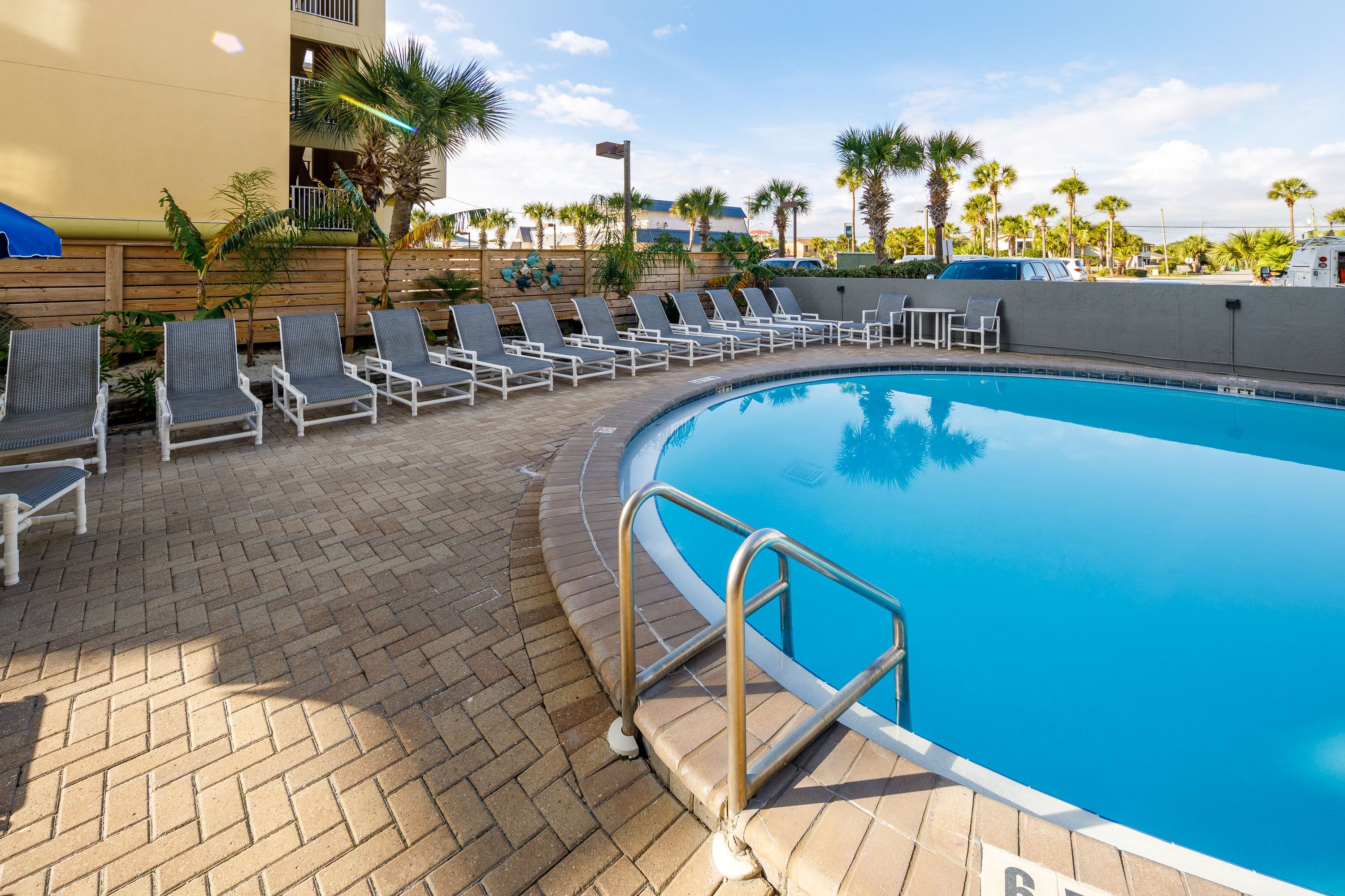 A pool area with lounge chairs and a brick walkway.
