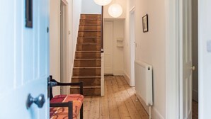 A hallway with a wooden staircase, white walls, and a radiator. - Large family home in Sandwich - Poplar House (Sandwich)