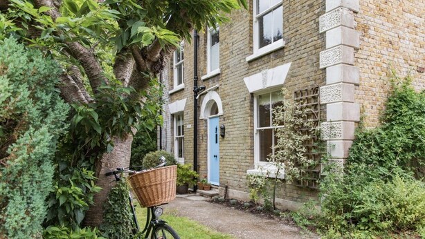 A bicycle with a basket parked against a brick building with a blue door. - Large family home in Sandwich - Poplar House (Sandwich)