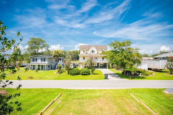 A residential neighborhood with a two-story house featuring a front porch, a driveway, and a well-maintained lawn.