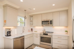 A modern kitchen with white cabinetry, stainless steel appliances, and a dishwasher.