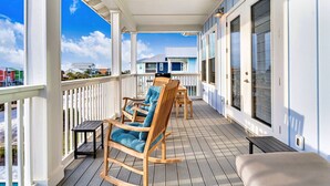 A covered outdoor area with wooden rocking chairs and a table, white railings, and large windows. - Gulfview new construction w/private, heated pool and beach gear! (Port St Joe)